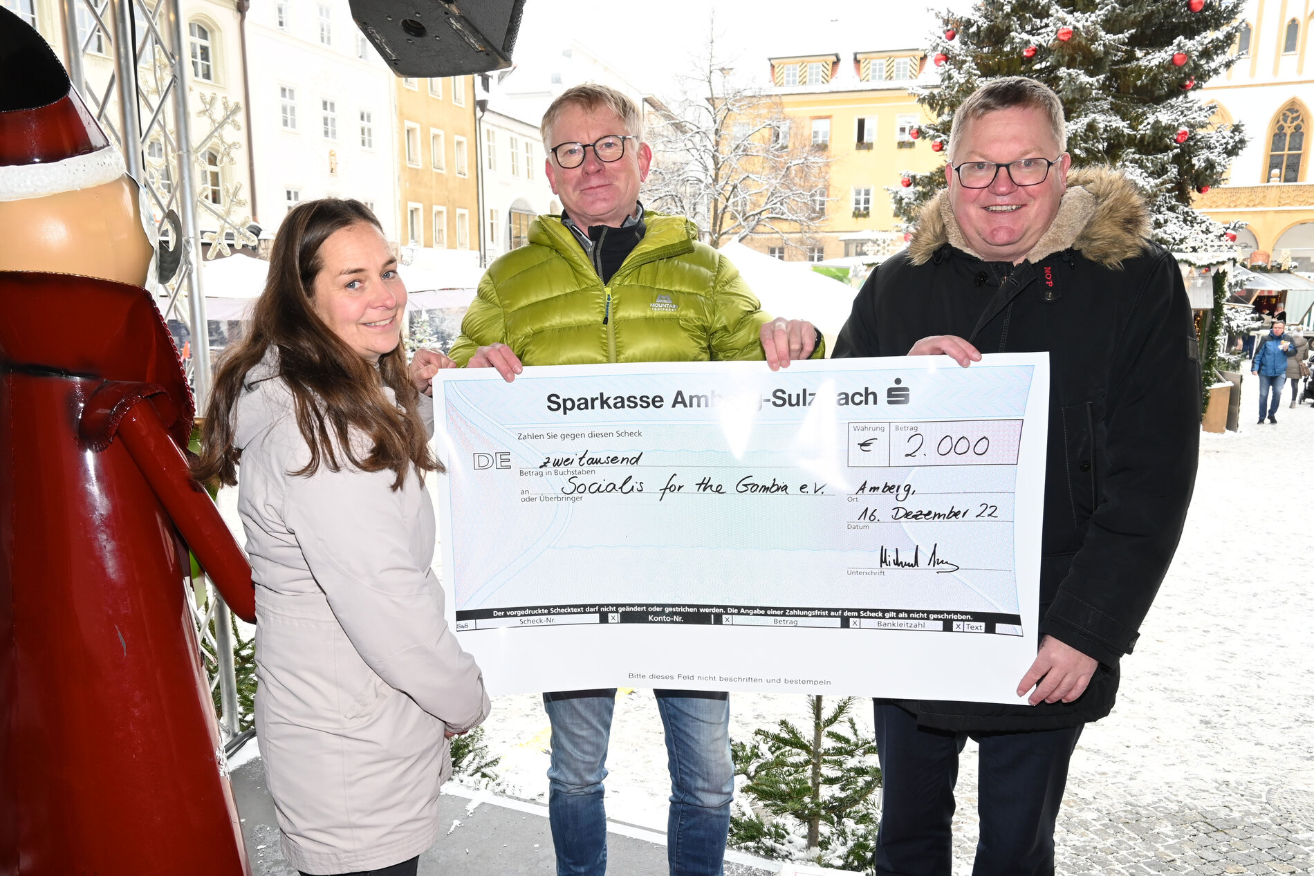 Das Bild zeigt, wie Oberbürgermeister Michael Cerny und die städtische Projektkoordinatorin Heike von Eyb einen Spendenscheck über 2000 Euro für das Projekt „1000 Schulen für unsere Welt“ an Thomas März-Kronfeld vom „Socialis for the Gambia“ übergeben.